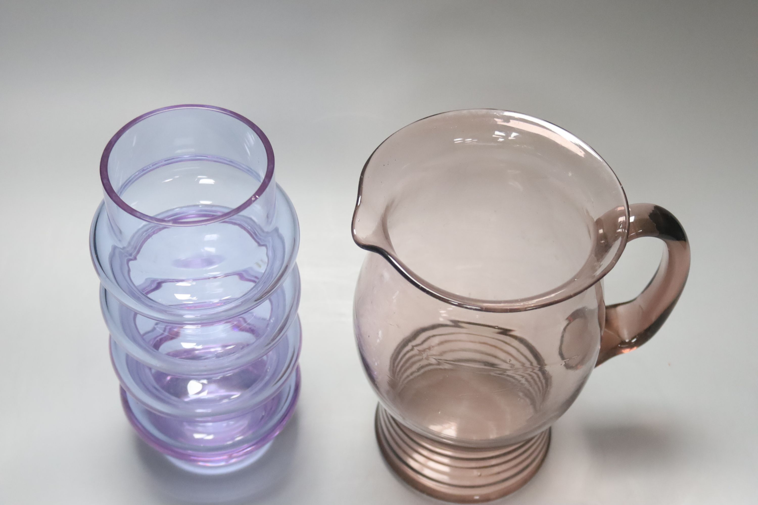 An Art glass pale amethyst jug with ribbed foot and a pale blue glass cylindrical ring-form vase, height 21cm